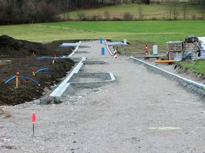 Picture depicting the beginning work of a development project, mounds of dirt, gravel  and pallets. 