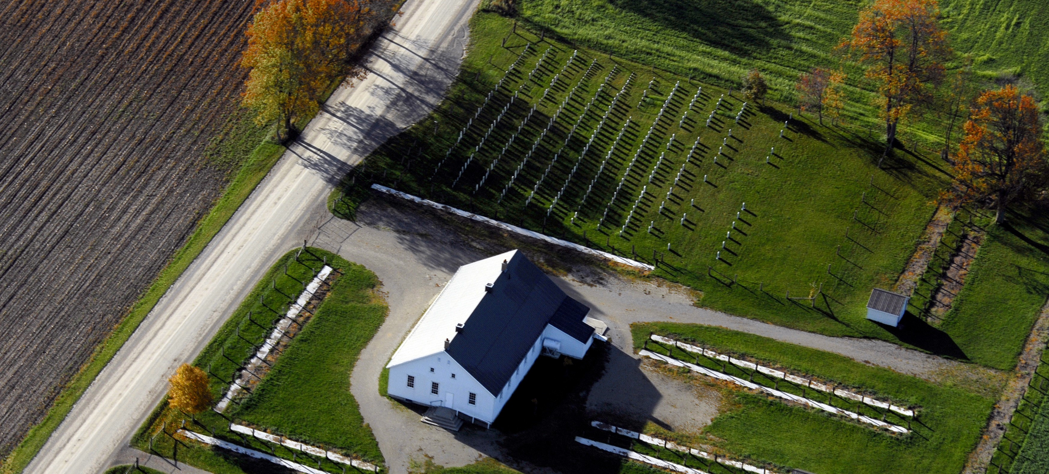 Aerial view of a small church and cemetery on a warm fall afternoon